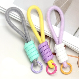 Three assorted colorful woven rope keychains with spring ring metal clasps on a clean background