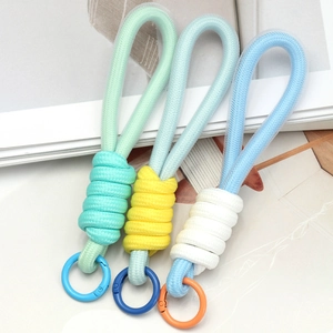 Three colorful woven paracord keychains with carabiners on a minimalist background