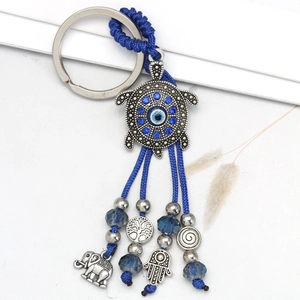Detail of evil eye keychain with silver turtle charm, blue tassels, and Hamsa hand symbols