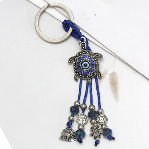 Detail of silver turtle evil eye keychain with blue tassels and hamsa hand charms