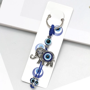 Detailed close-up of a silver elephant evil eye keychain on a white display card