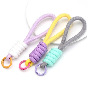 Close-up of multicolored braided rope keychains with metal spring ring clasps in a dish