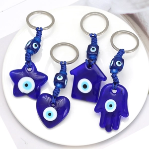 Blue Turkish evil eye keychains in star, heart, house and Hamsa hand shapes on a tray
