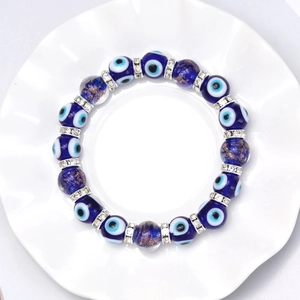 Blue Evil Eye beaded bracelet with silver rhinestone spacers on a white ceramic plate