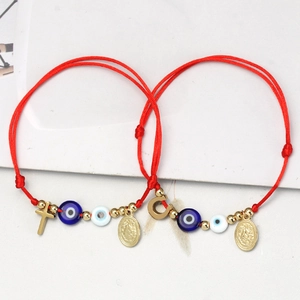 Nahaufnahme von roten Armbändern mit bösem Blick und religiösen Goldmedaillen