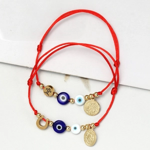 Detailansicht der roten Seilarmbänder mit Evil-Eye-Perlen und goldenen Anhängern