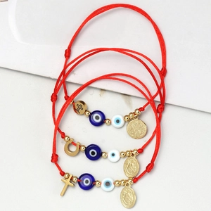 Detailansicht roter gewebter Armbänder mit Evil Eye Perlen und goldenen Anhängern auf Marmor