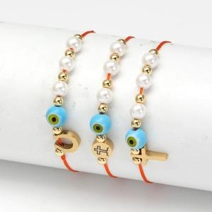 Detaillierte Makroansicht von gewebten Evil Eye Armbändern mit Goldanhängern und Perlen