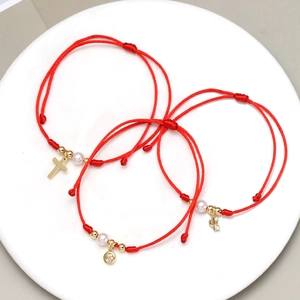 Detailansicht von drei roten Kordelarmbändern mit Kreuz, Smiley und Kaktus-Anhängern