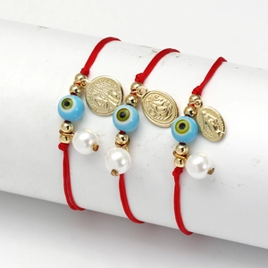 Detail von roten geflochtenen Armbändern mit blauen Evil Eye Perlen und Goldanhängern