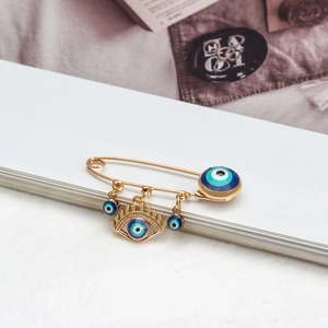 Detailansicht der goldenen Evil Eye Brosche mit mehreren Anhängern auf Vintage-Hintergrund