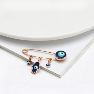 Detail einer goldenen Evil Eye Sicherheitsnadel-Brosche mit Hamsa-Hand-Anhängern