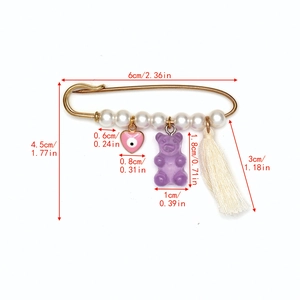 Détail de l'épingle Evil Eye avec perles, cœur rose, ours en résine et pompon blanc