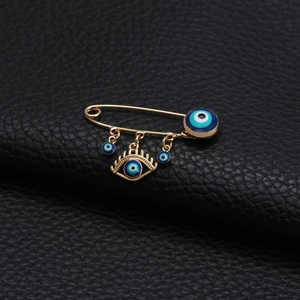 Makro-Detail der goldenen Evil Eye Brosche mit blauen Emaille-Anhängern auf Leder