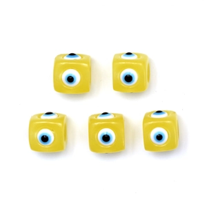 Macro detail of square yellow beads with blue evil eye pattern for DIY jewelry making