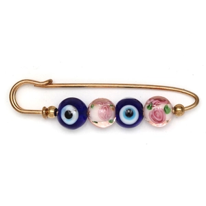 Detail view of a gold safety pin brooch with blue evil eye and floral crystal beads
