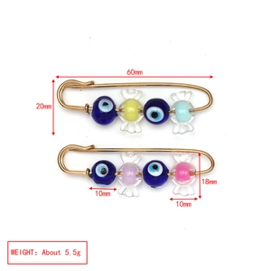 Detailed view of evil eye and candy bead safety pins with 60mm length measurements