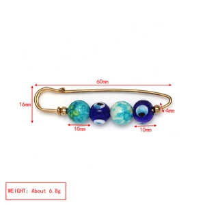 Detailed view of evil eye safety pin brooch with blue beads and golden metal finish