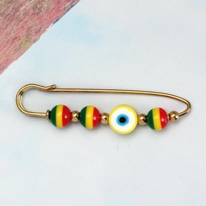 Detailed close-up of gold safety pin brooch with devil eye and striped colorful beads