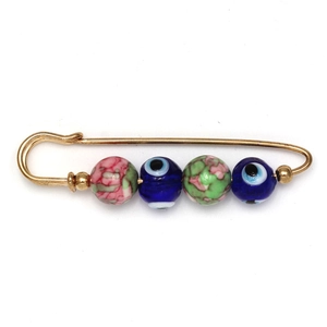 Detailed view of evil eye brooch pin with pink marble beads and gold safety pin accents