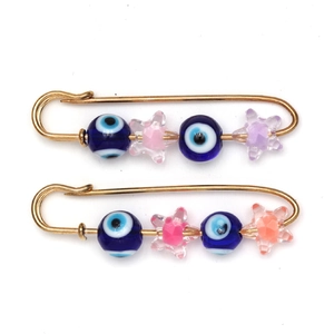 Detailed view of two gold safety pins with blue evil eye beads and colorful matte star beads