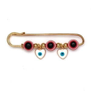 Detail van de Evil Eye-bedeltjes en witte hartjes aan een gouden veiligheidsspeld