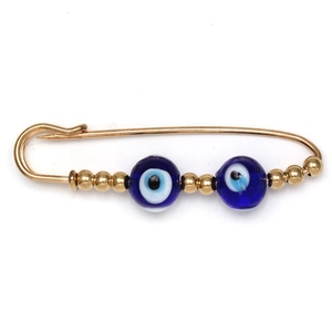 Close-up of golden evil eye safety pin brooch with blue beads and metallic accents