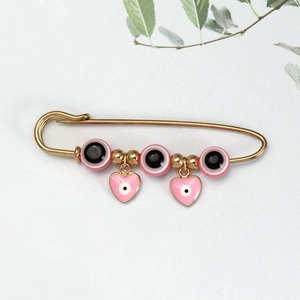 Detailweergave van de gouden Evil Eye broche met roze hartbedeltjes en emaille kralen