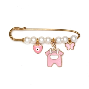 Détail d'une broche dorée avec sept perles et breloques émaillées roses pour bébé