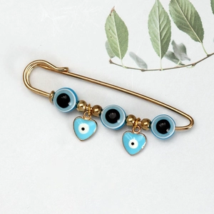 Detailopname van de gouden veiligheidsspeld broche met blauwe boze oog hangers