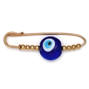 Detail of a golden safety pin brooch featuring a blue evil eye bead and gold beads