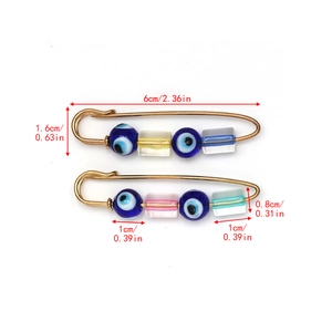 Detail view of gold safety pins with blue evil eyes and colorful candy beads