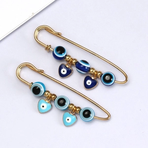 Detailweergave van gouden Evil Eye veiligheidsspelden met hartjes en blauwe kralen
