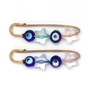 Detail of DIY Evil Eye safety pins with blue glass beads and star charms on gold metal