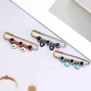 Gedetailleerde macro-opname van vergulde Evil Eye-spelden met hartbedels in drie kleuren
