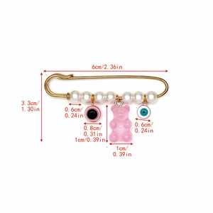 Détail montrant la dimension de la broche œil avec perle et pendentif ours rose