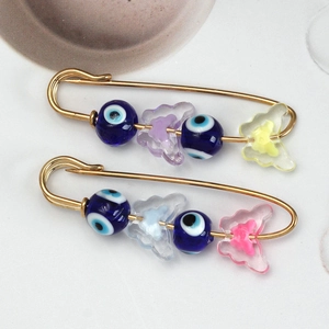 Macro view of gold Turkish evil eye brooches with colorful butterfly beads