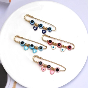 Gouden Evil Eye veiligheidsspelden met emaille kralen en hartjes op een wit keramieken bord