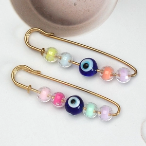 Macro view of gold safety pins with colorful glass beads and blue evil eye charms