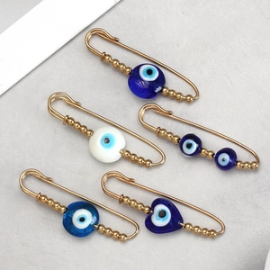 Detailed macro shot showing a set of 5 golden evil eye pins with blue bead accents