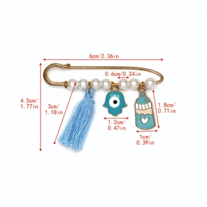 Vue détaillée de la broche épingle Evil Eye avec glands bleus, perles et breloque Hamsa