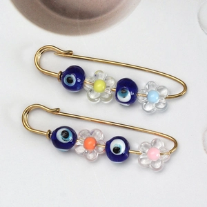 Macro shot of evil eye candy brooches with colorful flower beads and golden metal pins