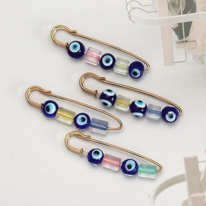 Detail view of 4-piece set of gold safety pins with blue evil eye beads and glass cubes