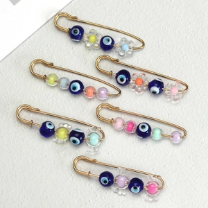 Macro detail of six gold-plated Evil Eye brooches with colorful candy and flower beads
