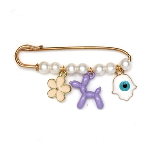 Détail de broche dorée à pompon avec œil protecteur, fleur rose et perles blanches
