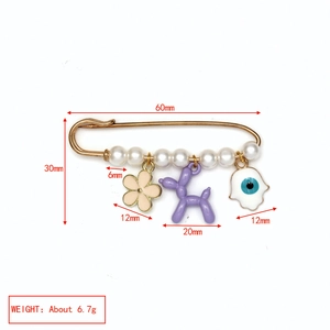 Détail de la broche mauvais œil avec perles blanches, fleur rose et breloque chien ballon