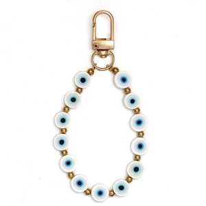 Macro view of white beads with blue evil eye charms and golden metal lobster clasp