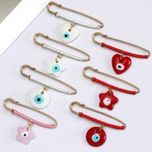 Detail of seven gold pins with evil eye charms in heart, star and round shapes