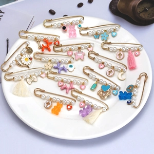 Broche pampille mauvais œil avec perles et charms sur une assiette décorative