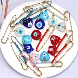 Detail of colorful Evil Eye safety pin brooches with heart and star glass charms